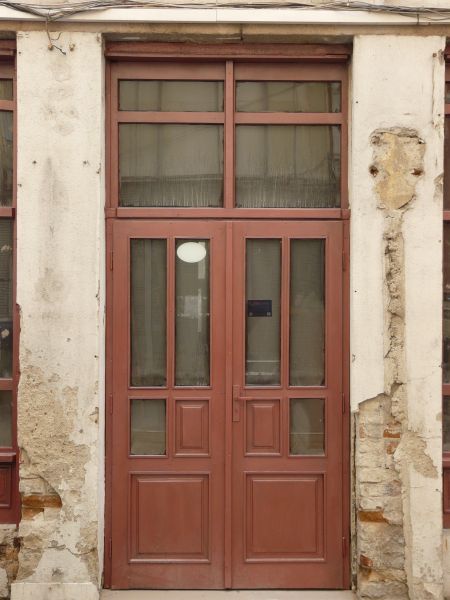 Tall wooden doors in dark red tone with glass windows.